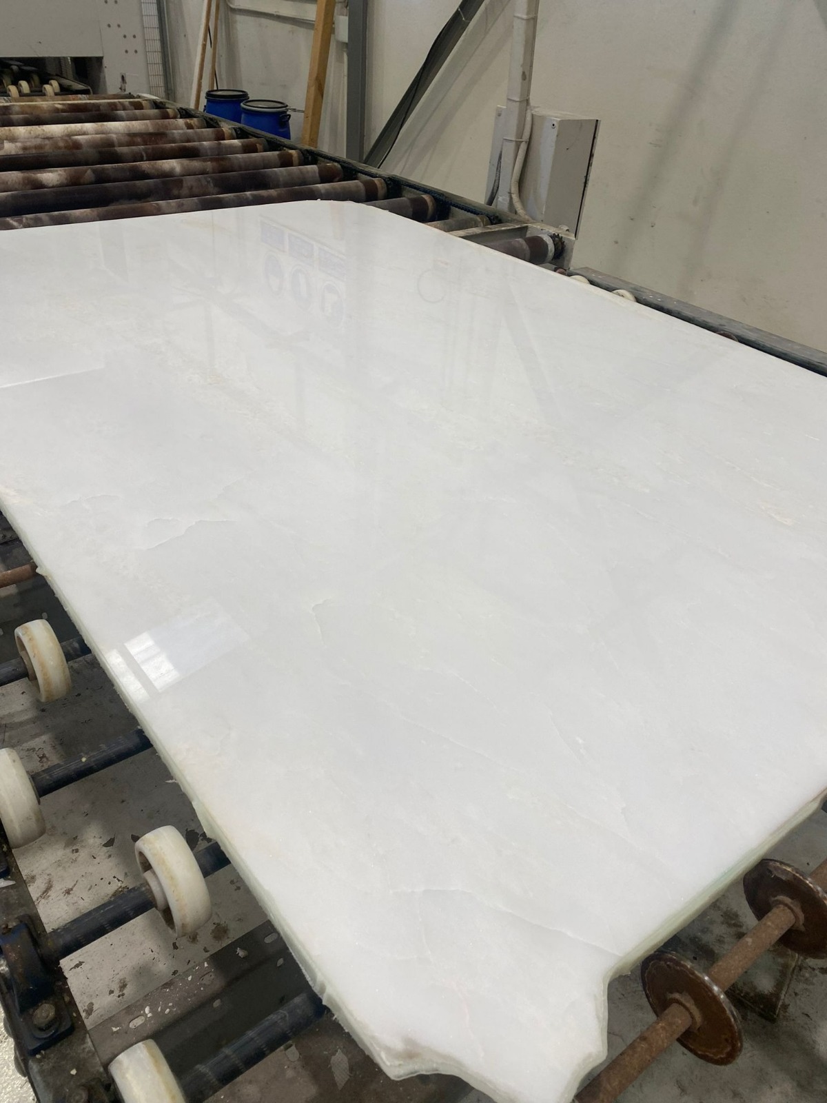 Слеб мрамора намбия вайт в процессе полировки на фабрике неподалеку от каръера